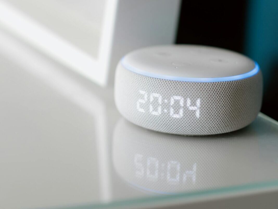 Close-up of a smart speaker with digital time display indoors.