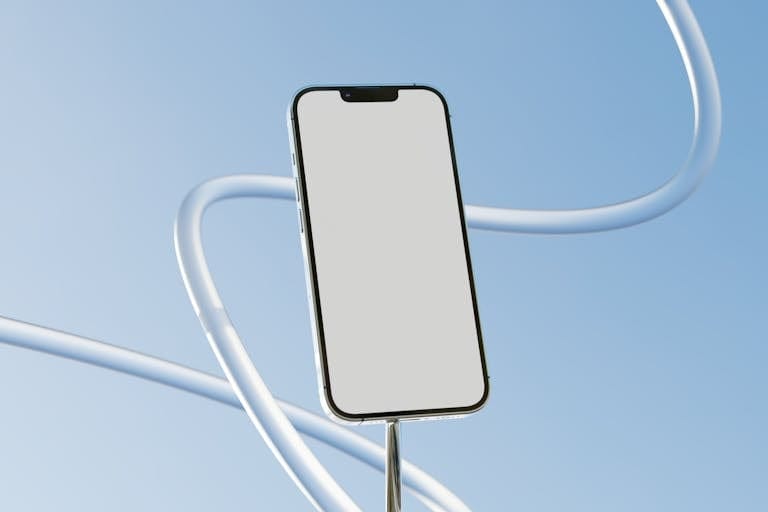 Minimalist smartphone mockup with blank screen against a clear blue sky, ideal for tech presentations.